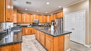 A spacious kitchen with wooden cabinets, granite countertops, stainless steel appliances, and a large island.