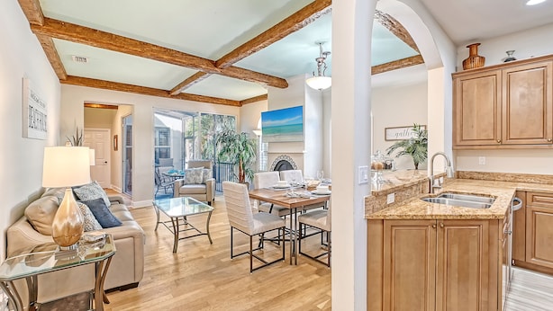 A spacious living area with a wooden ceiling, a dining table, and a kitchen with wooden cabinets and a granite countertop.