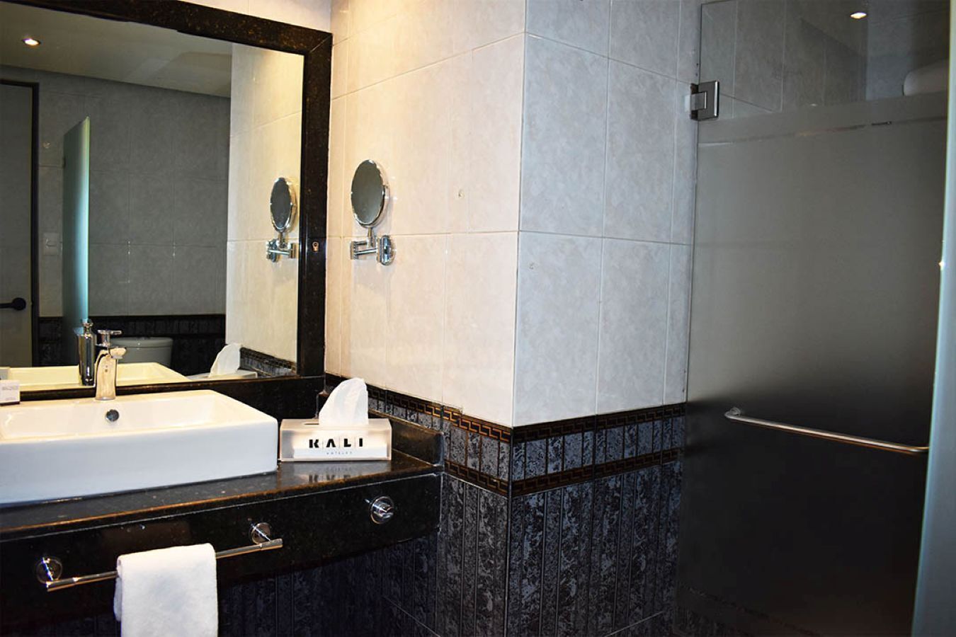 A modern bathroom with a large mirror, two sinks, and a towel rack.