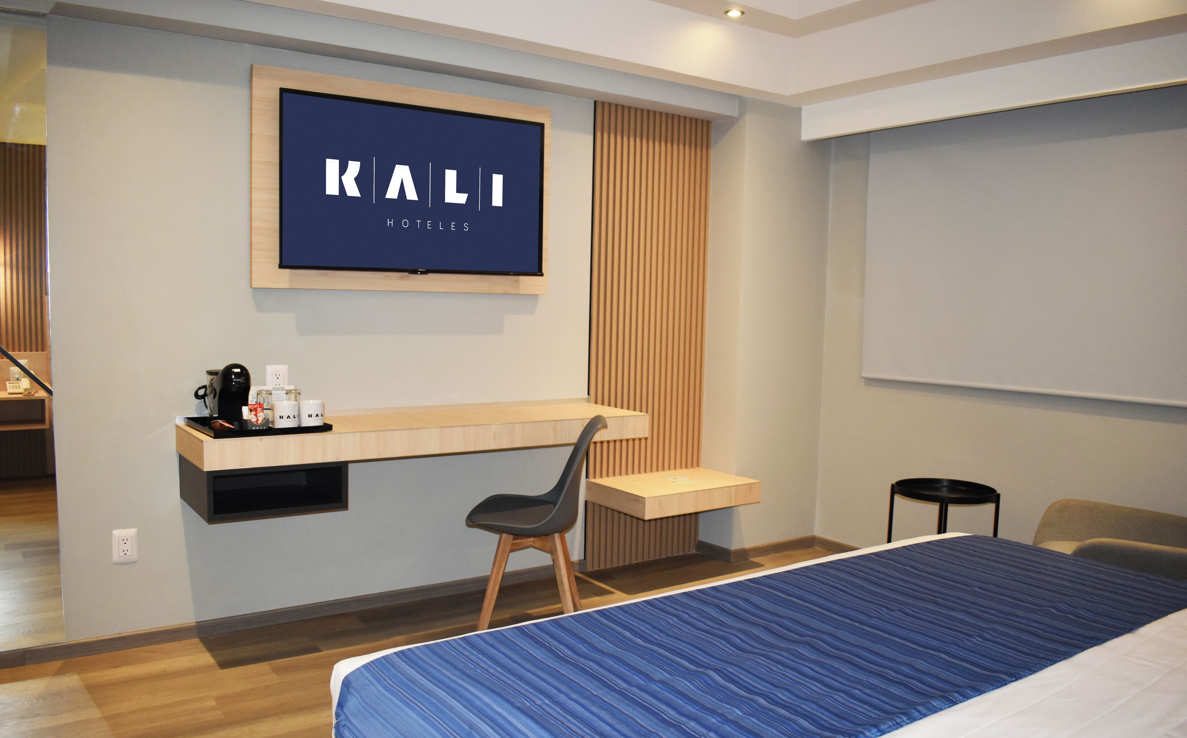 A hotel room with a bed, a desk, a chair, a television, and a projector screen.