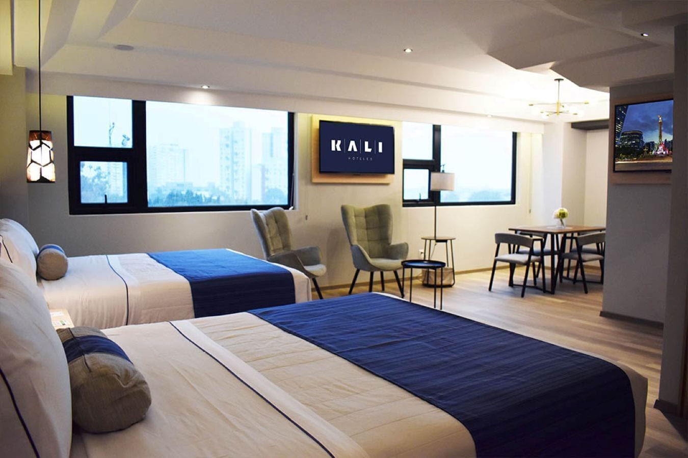 Ein Hotelzimmer mit zwei Betten, einem Schreibtisch, einem Stuhl und einem Fernseher.