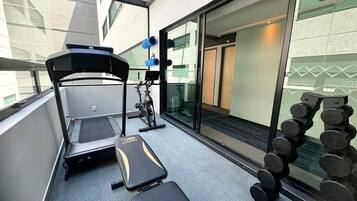 Une salle de sport équipée d’un tapis de course, d’un banc de musculation, d’haltères et d’un vélo d’appartement.