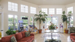 A spacious lobby with a red sofa, a glass coffee table, and potted plants.