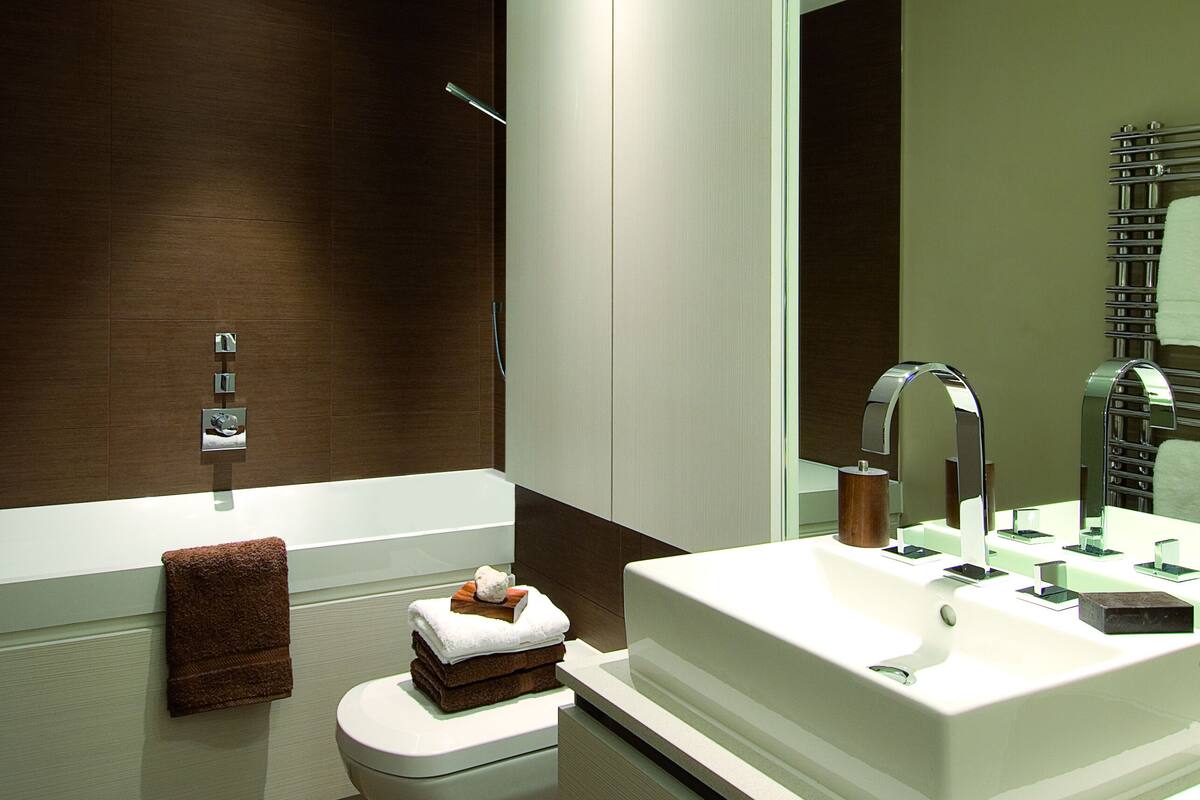 Une salle de bain moderne avec un lavabo blanc, des toilettes et un grand miroir.