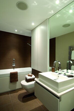 Ein modernes Badezimmer mit einem weißen Waschbecken, einer Toilette und einem großen Spiegel.