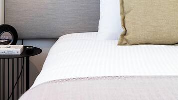 A neatly made bed with a headboard, a bedside table with a lamp, and a framed picture on the wall.