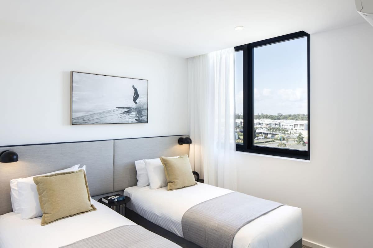 Habitación de hotel con dos camas, vista a la ciudad y un cuadro en la pared.