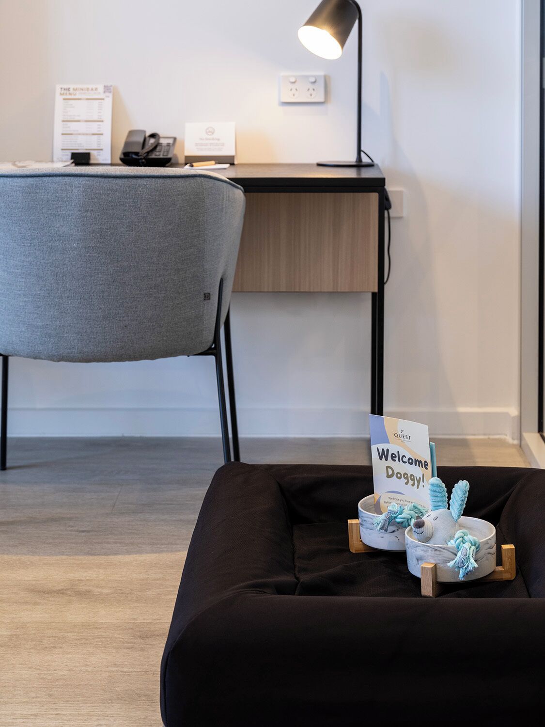 A modern room with a desk, chair, and a welcome sign for guests.