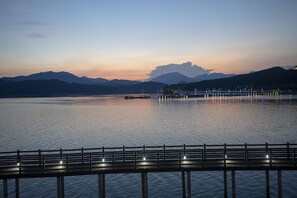A waterfront view with a wooden pier and a distant cityscape. - Ocean Spa Hotel (Goseong)