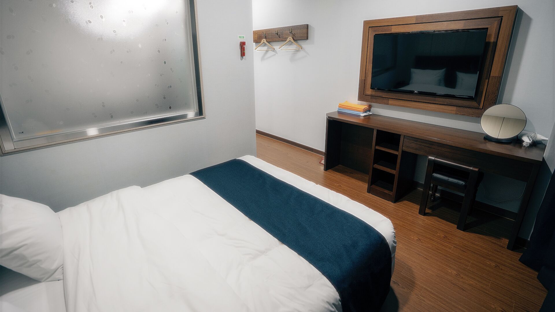 Una habitación de hotel con una cama, un escritorio con espejo y un televisor.
