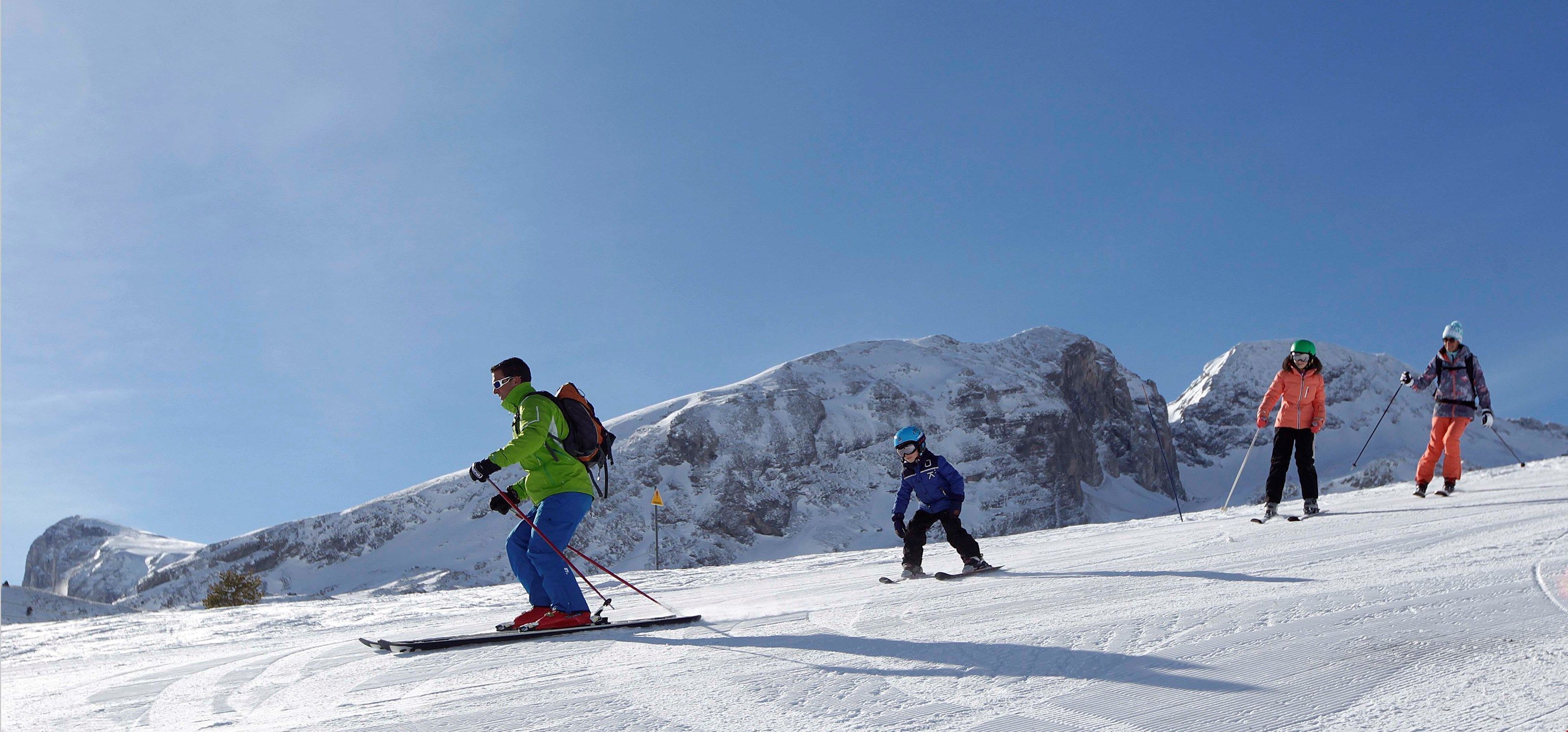 Esquiadors en una vessant nevada amb muntanyes al fons.