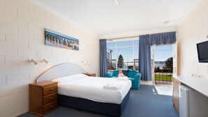 A hotel room with a bed, a dresser, a desk, a TV, a window with curtains, and a painting on the wall. - Blue Seas Motel (Port Lincoln)