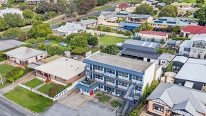 An aerial view of a motel with a two-story structure, a parking lot, and surrounding residential houses. - Blue Seas Motel (Port Lincoln)