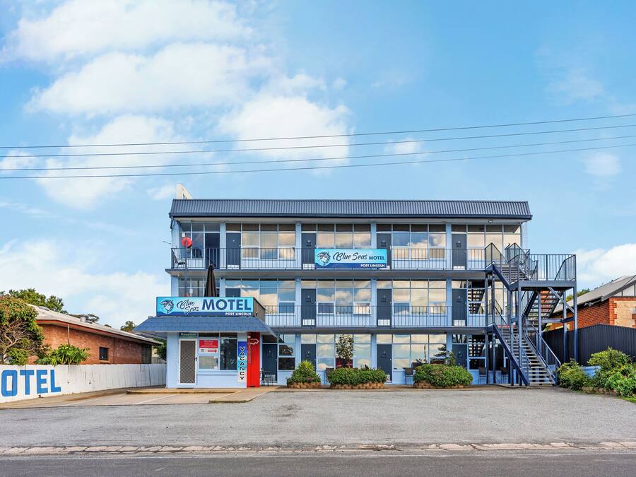 Un motel con struttura su due piani, un ingresso ben visibile e un cartello che indica che si tratta del Olive Seas Motel a Fort Lincoln.