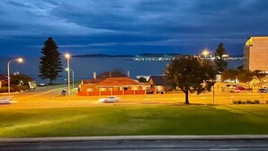 A coastal road with buildings, a tree, and a distant view of a bridge. - Blue Seas Motel (Port Lincoln)