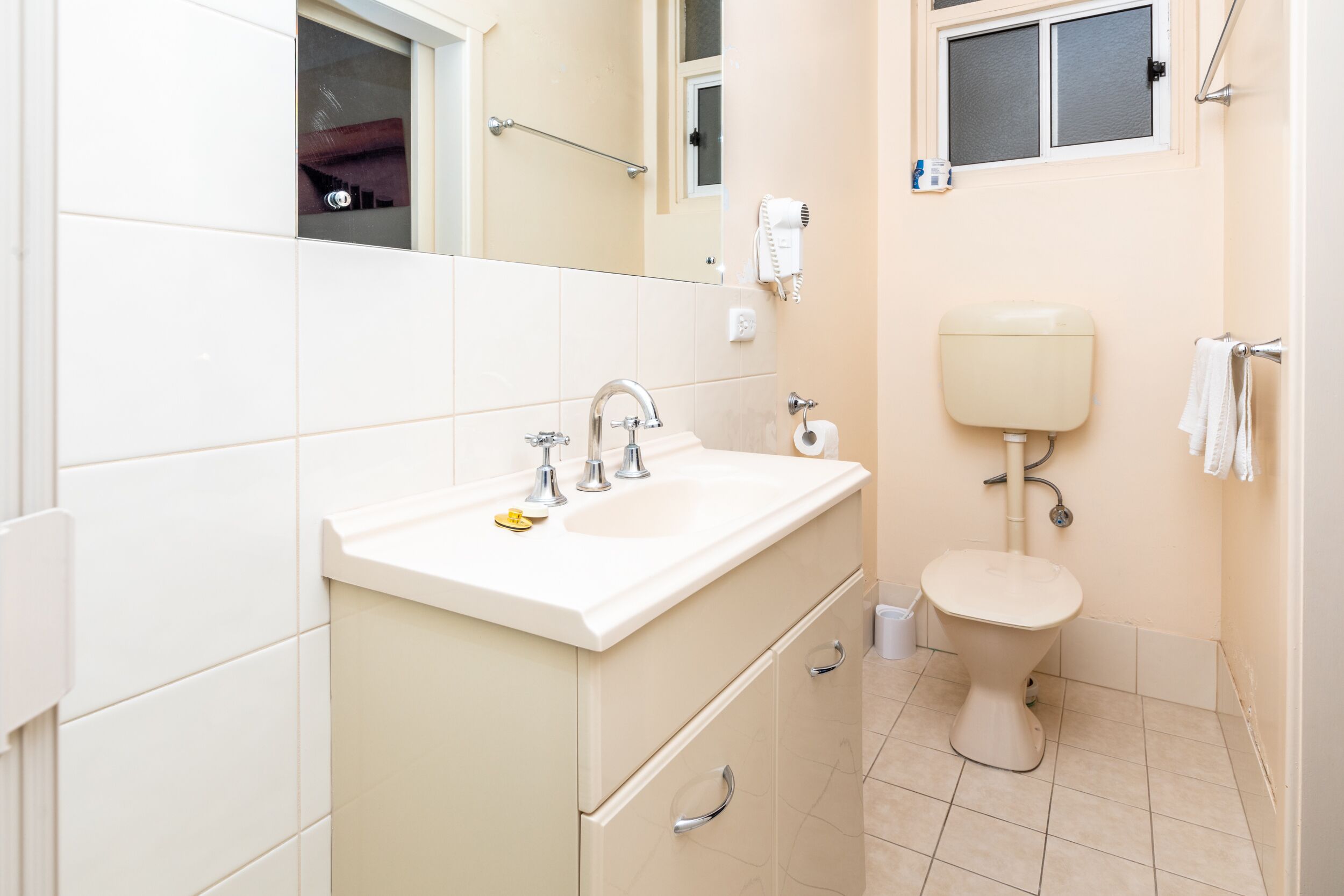 A bathroom with a sink, mirror, toilet, and towel rack.
