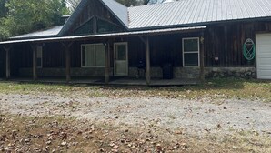 A rustic cabin with a covered porch, stone foundation, and a metal roof.