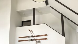 Una cuina moderna amb un frigorífic blanc, un rellotge i una zona de dinar amb taula i cadires de fusta.
