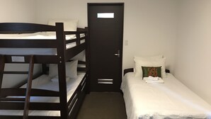 Habitació amb literes, una porta i un llit individual.