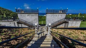 A staircase leading to a concrete structure with railings and lamp posts, overlooking a coastal area.