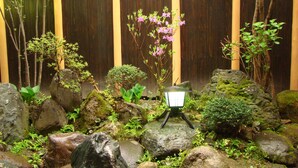 A rock garden with a small table and a lantern, surrounded by various plants and rocks. - Azuma Ryokan (Kitakata)