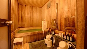 A wooden sauna room with a bathtub, a small stool, a toilet, and a shelf with bottles. - Azuma Ryokan (Kitakata)