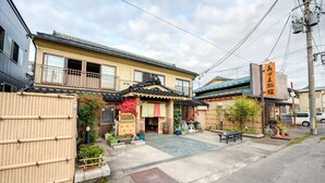 A traditional Japanese house with a tatami mat entrance, a small garden, and a bicycle parked outside. - Azuma Ryokan (Kitakata)