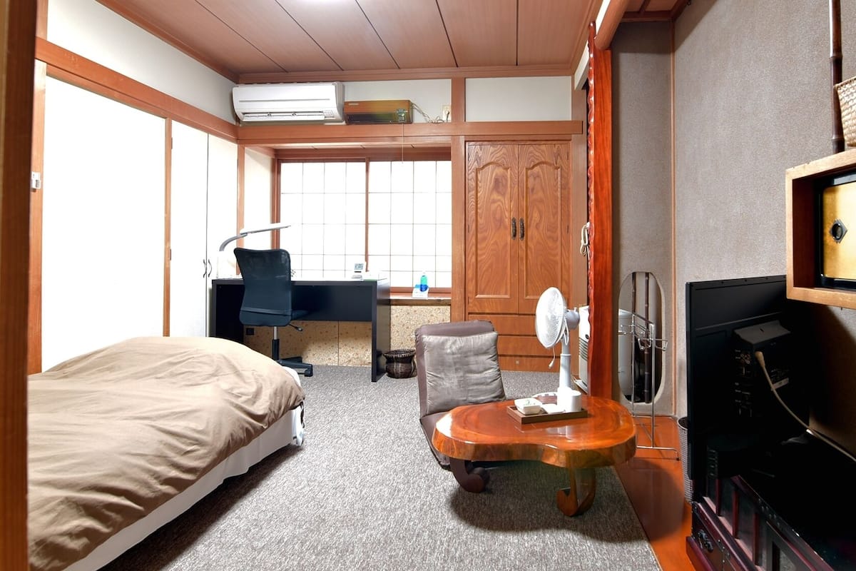 Habitación de hotel con cama, escritorio, silla y televisor.
