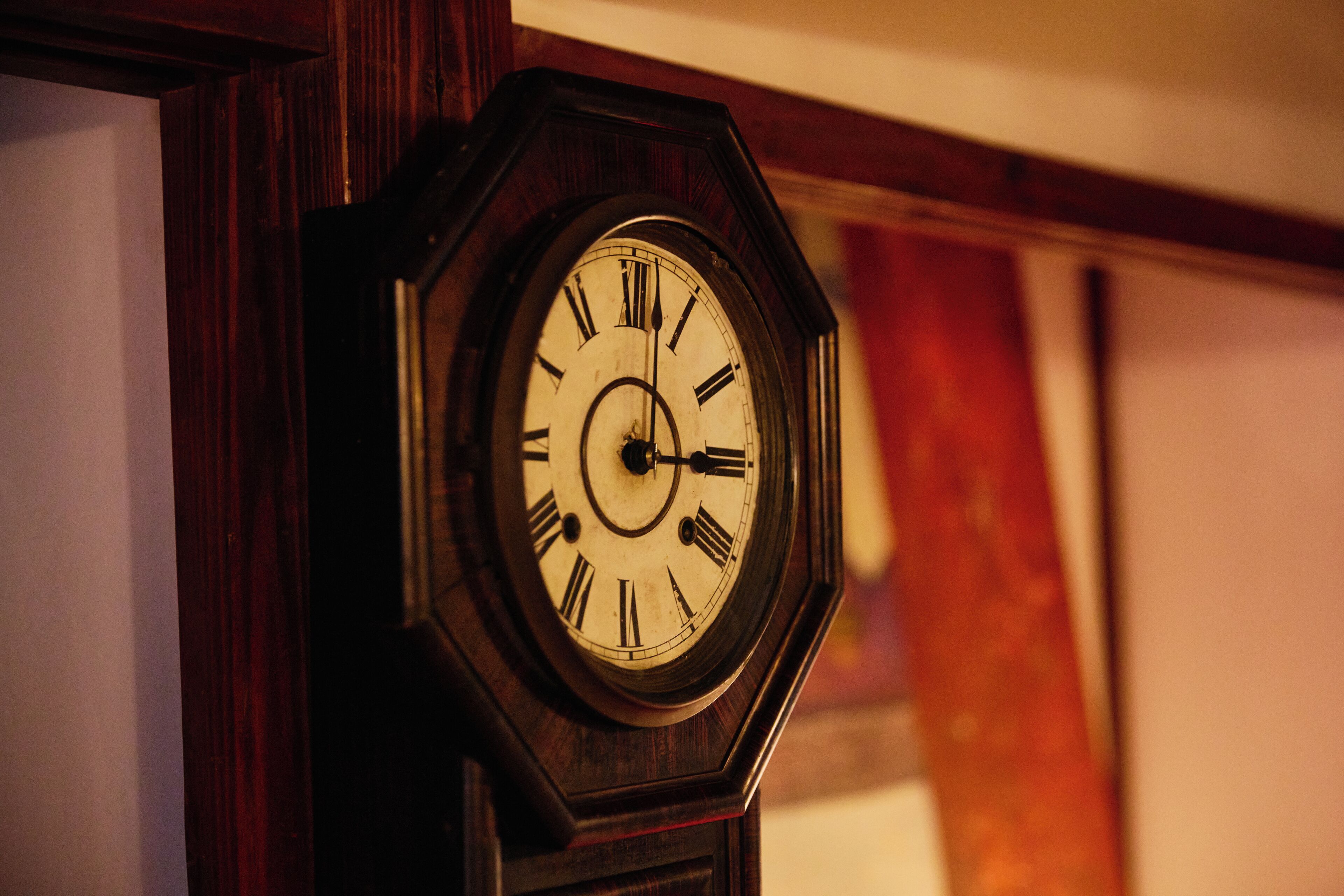 A close-up of a wooden grandfather clock with Roman numerals.