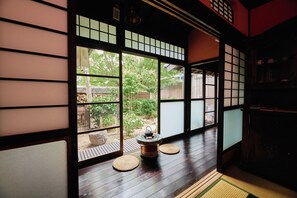 Une pièce de style japonais traditionnel, avec un sol recouvert de tatamis, des paravents shoji et une vue sur le jardin.
