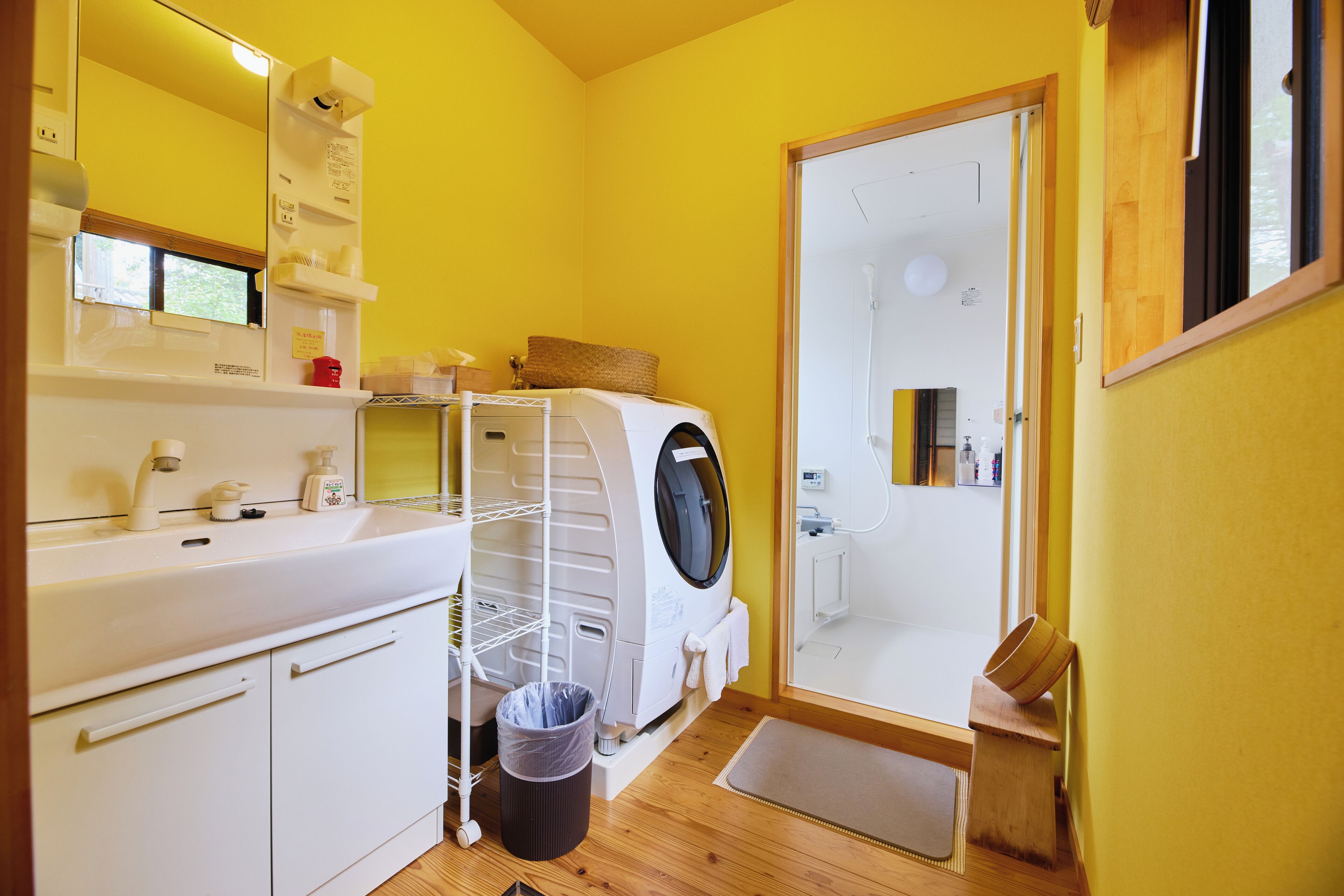 Ein kleines Badezimmer mit Waschmaschine, Waschbecken und Spiegel.