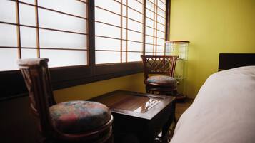 A room with a bed, a wooden table, a chair, and a lamp.