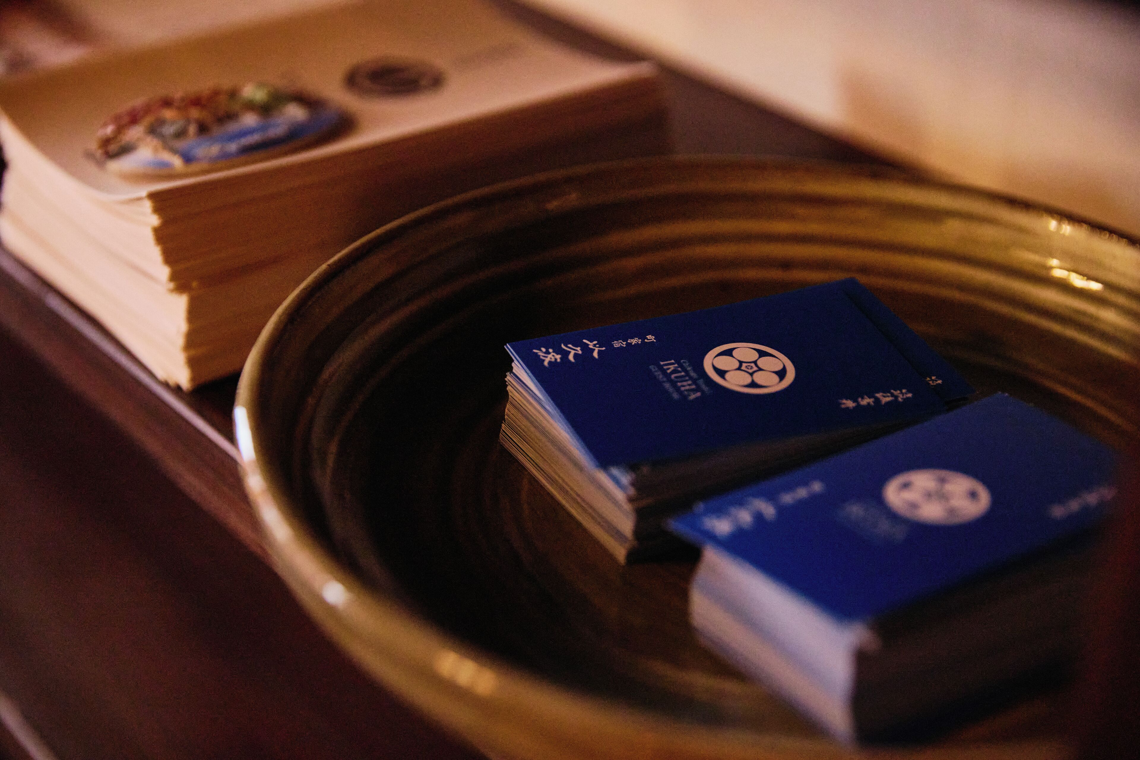 A stack of books and two blue boxes on a table.