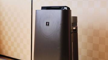 Un refrigerador Sharp negro en una habitación con un estampado de cuadros.