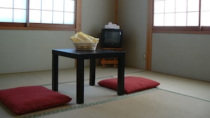 A traditional Japanese room with tatami flooring, a low table with a television, and a basket with cloths.