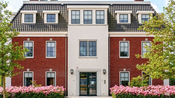 A two-story building with a symmetrical facade, featuring a central entrance with a glass door and windows on both sides. - Ganuenta by Interhome (Colijnsplaat)