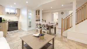 A modern kitchen with an oven, a dining area with a table and chairs, and a staircase with wooden railings.