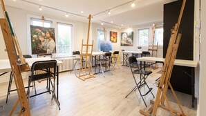 A spacious art studio with easels, tables, and chairs arranged for painting.