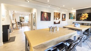 A spacious art studio with easels, a large painting, and art supplies on a table.