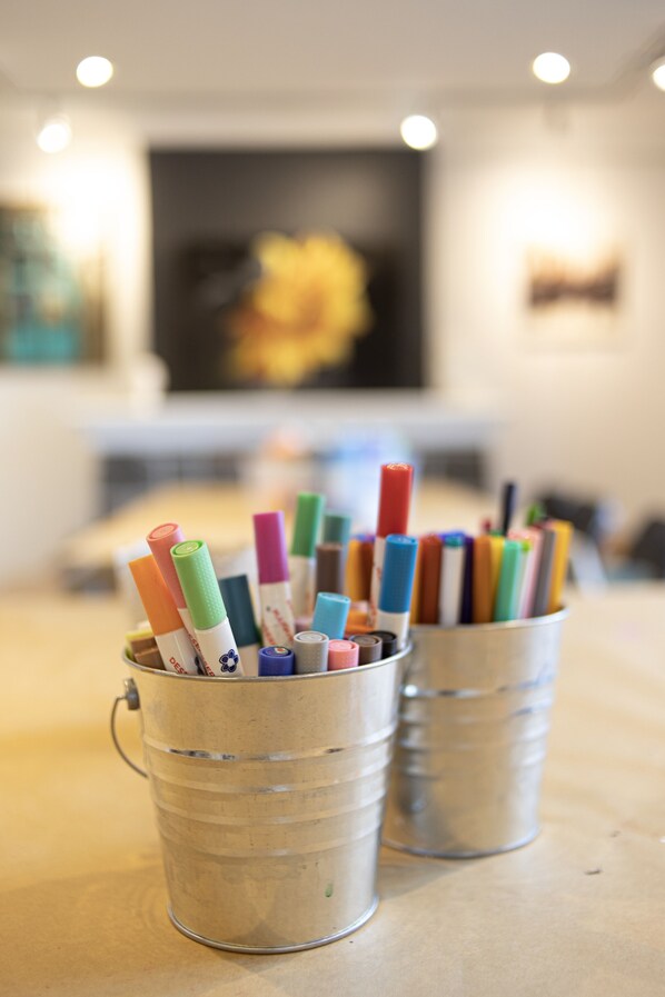 Two metal buckets filled with colorful markers on a table.