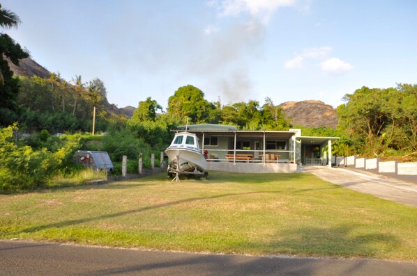 A boat docked in a grassy area with a building in the background.