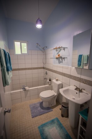 A bathroom with a bathtub, toilet, sink, and a mirror.