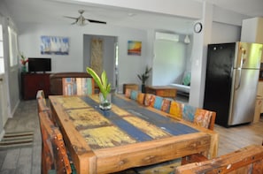 A dining area with a wooden table and chairs, a vase with a plant, and a black refrigerator.