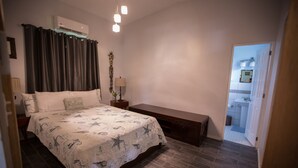 A bedroom with a bed, bedside table, lamp, and an air conditioning unit.