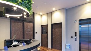 A hotel reception area with a modern design, including a reception desk, a digital display, and a wooden floor. - Hotel Halrotto Fukuoka Hakata (Fukuoka)