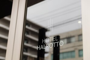 Een hotelschild met de naam 'HOTEL HALROTT' in een modern gebouw.