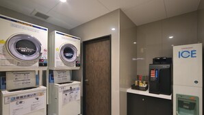 A laundry facility with two front-loading washers, a refrigerator, and a water dispenser. - Hotel Halrotto Fukuoka Hakata (Fukuoka)