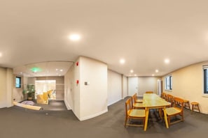 A conference room with a large table and chairs, a separate seating area with sofas, and a visible exit door. - Read and Rest Hotel (Beijing)