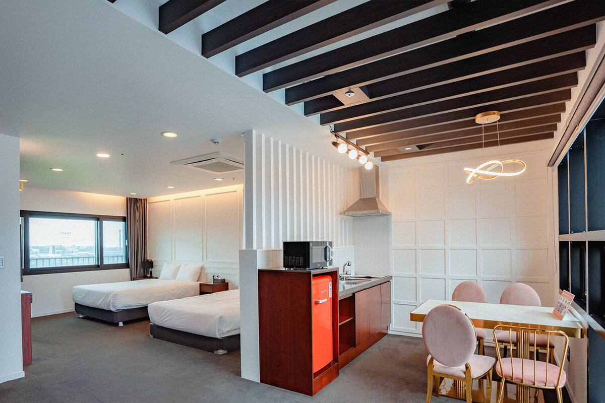 Una habitación de hotel moderna con una cama, un escritorio, una silla y un rincón de comedor.