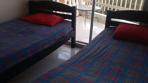 Two single beds with patterned bedspreads, a small table, and a balcony with a railing.